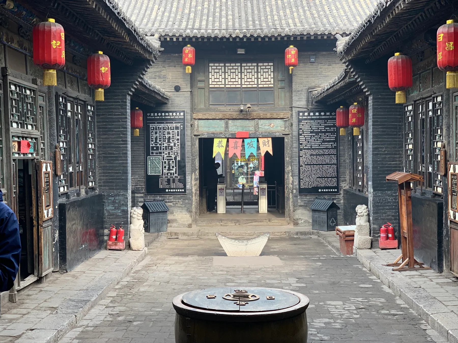 A traditional Pingyao courtyard with red lanterns and gray brick walls.