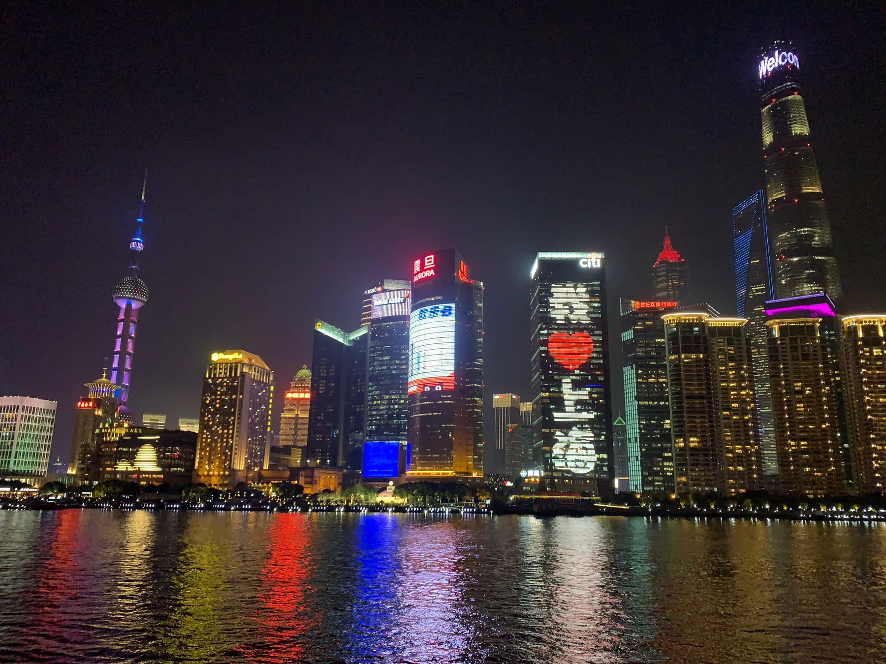 The Shanghai skyline lit up across the water at night.
