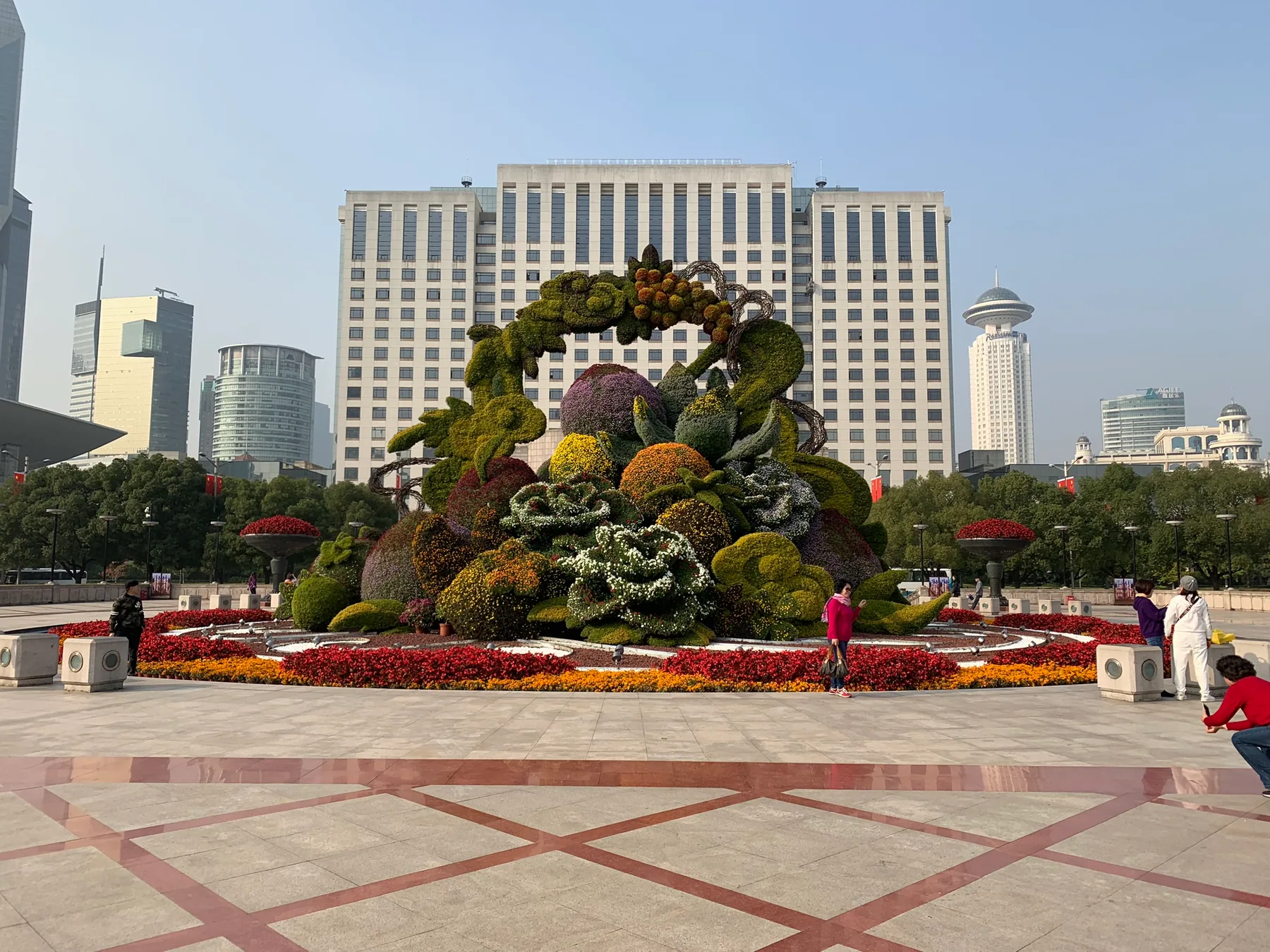 A Shanghai city square with a floral display and tall buildings.