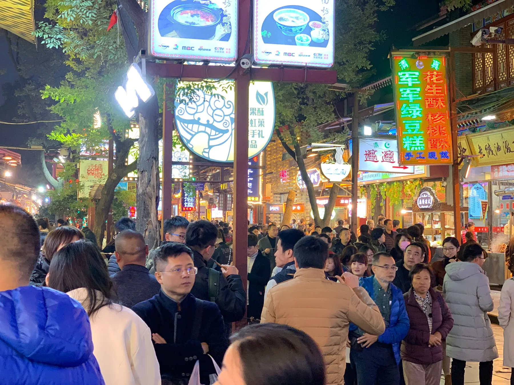 Food stalls and signs glowing at night in Xi’an's Muslim Quarter.