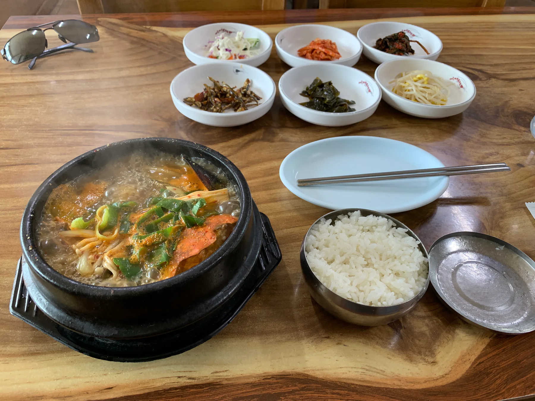 A hot meal with rice and side dishes on a wooden table in Jeju.