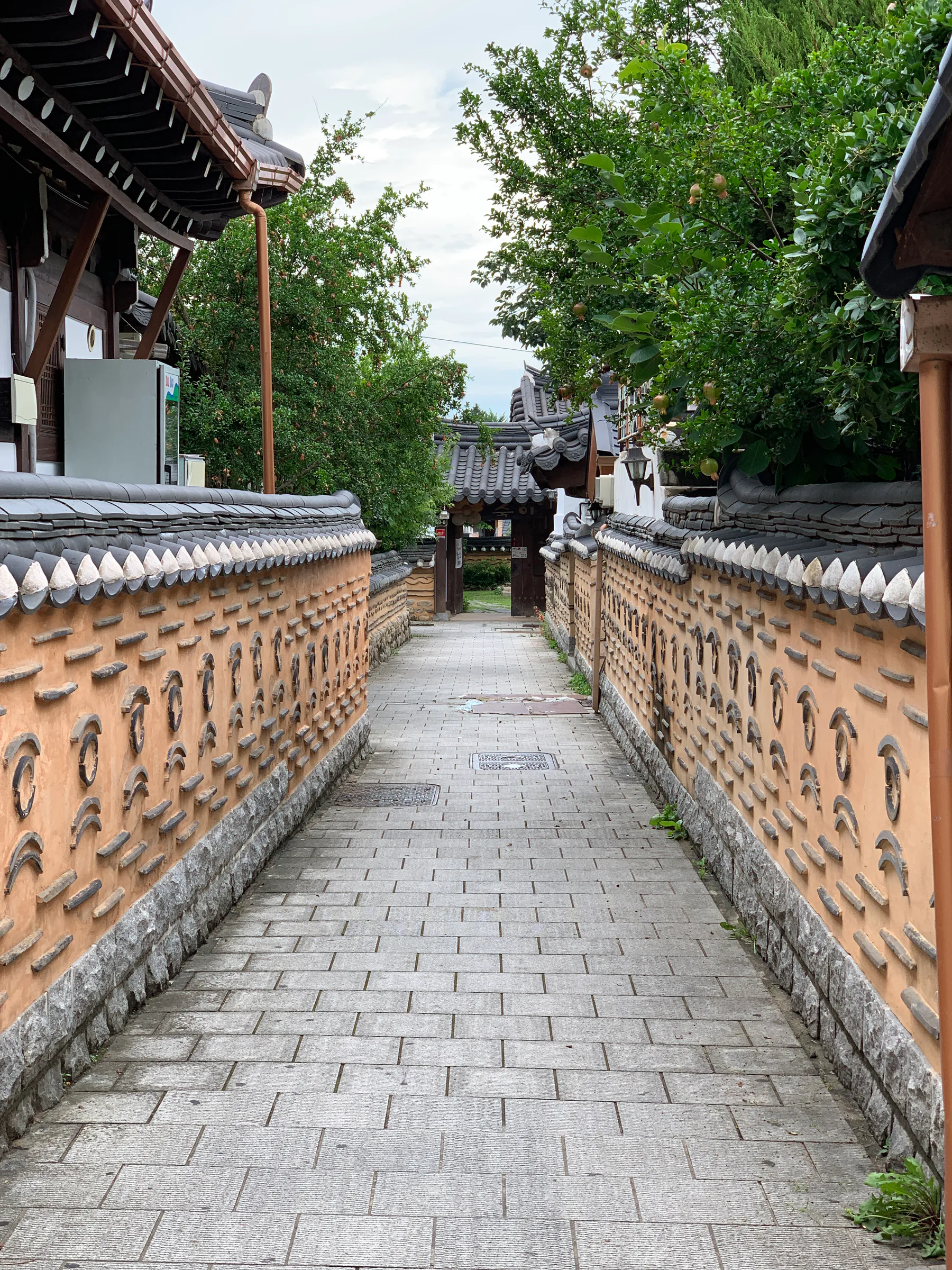 A narrow hanok alley with brick walls and traditional roofs in Jeonju.