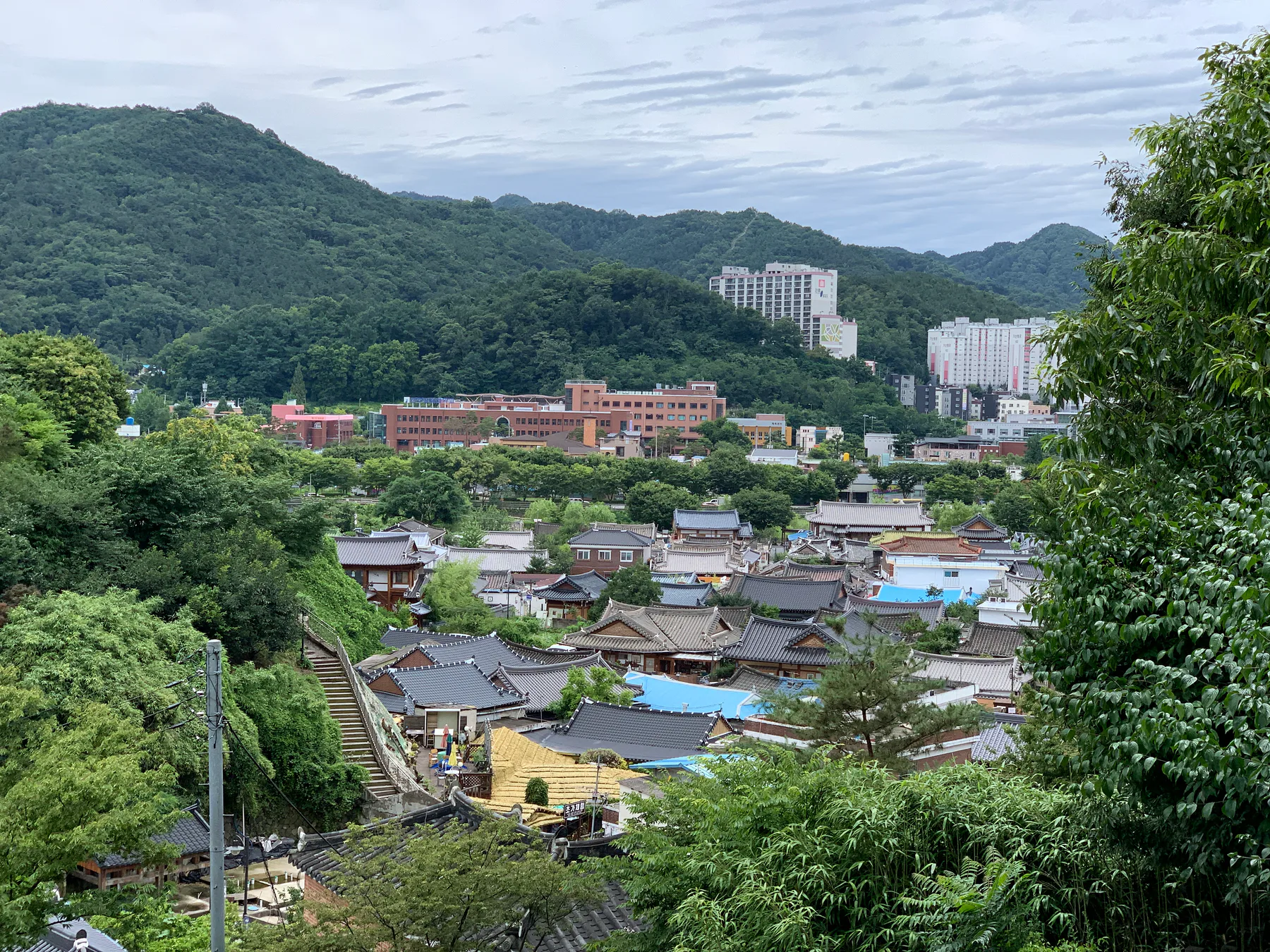 A hill view over Jeonju rooftops and surrounding green hills.
