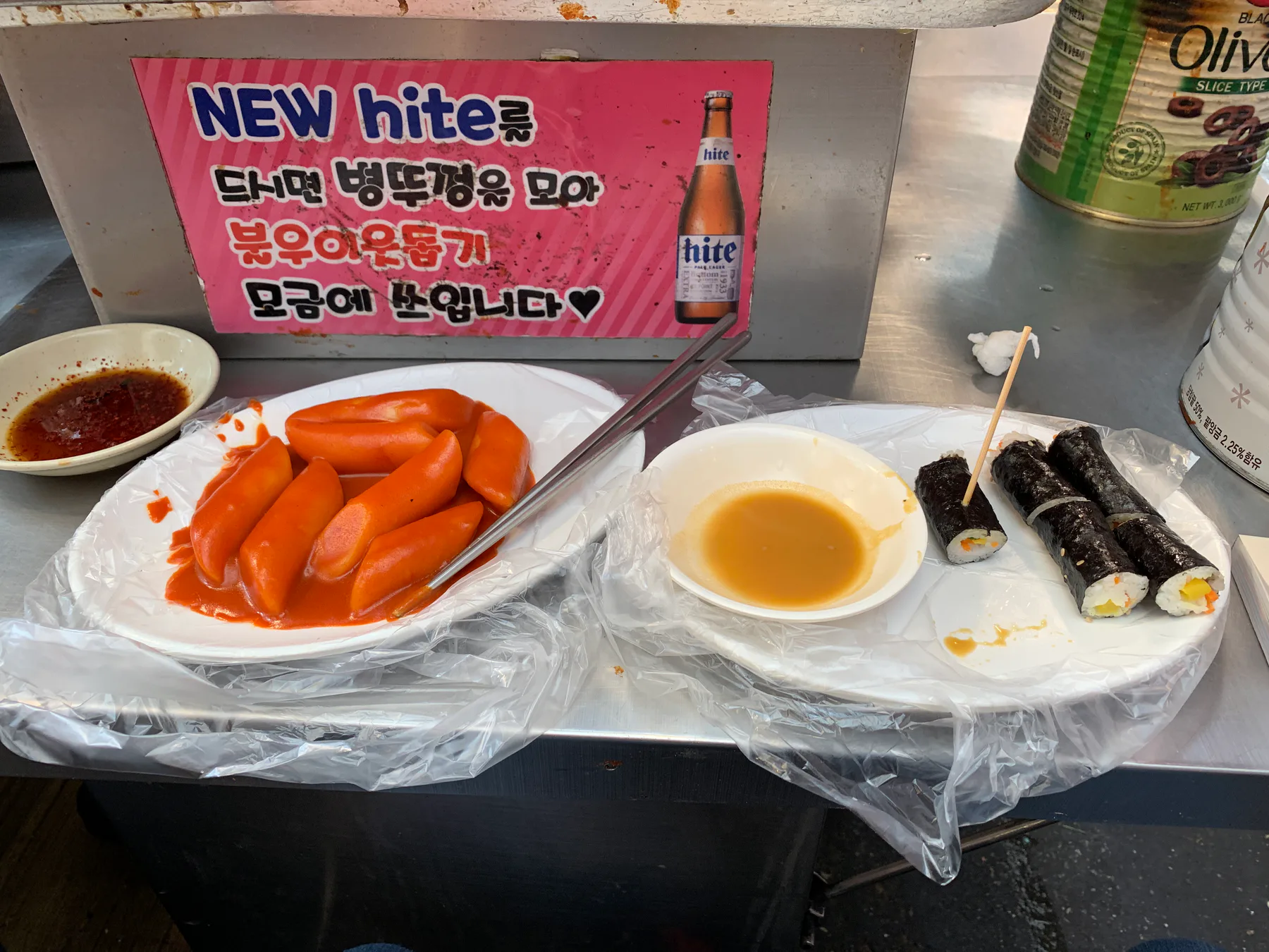 A plate of tteokbokki and gimbap on a market counter in Gwangjang Market.