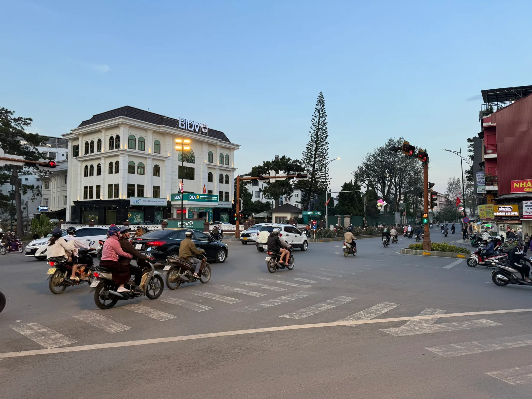 A Da Lat street with scooters moving past buildings at dusk.