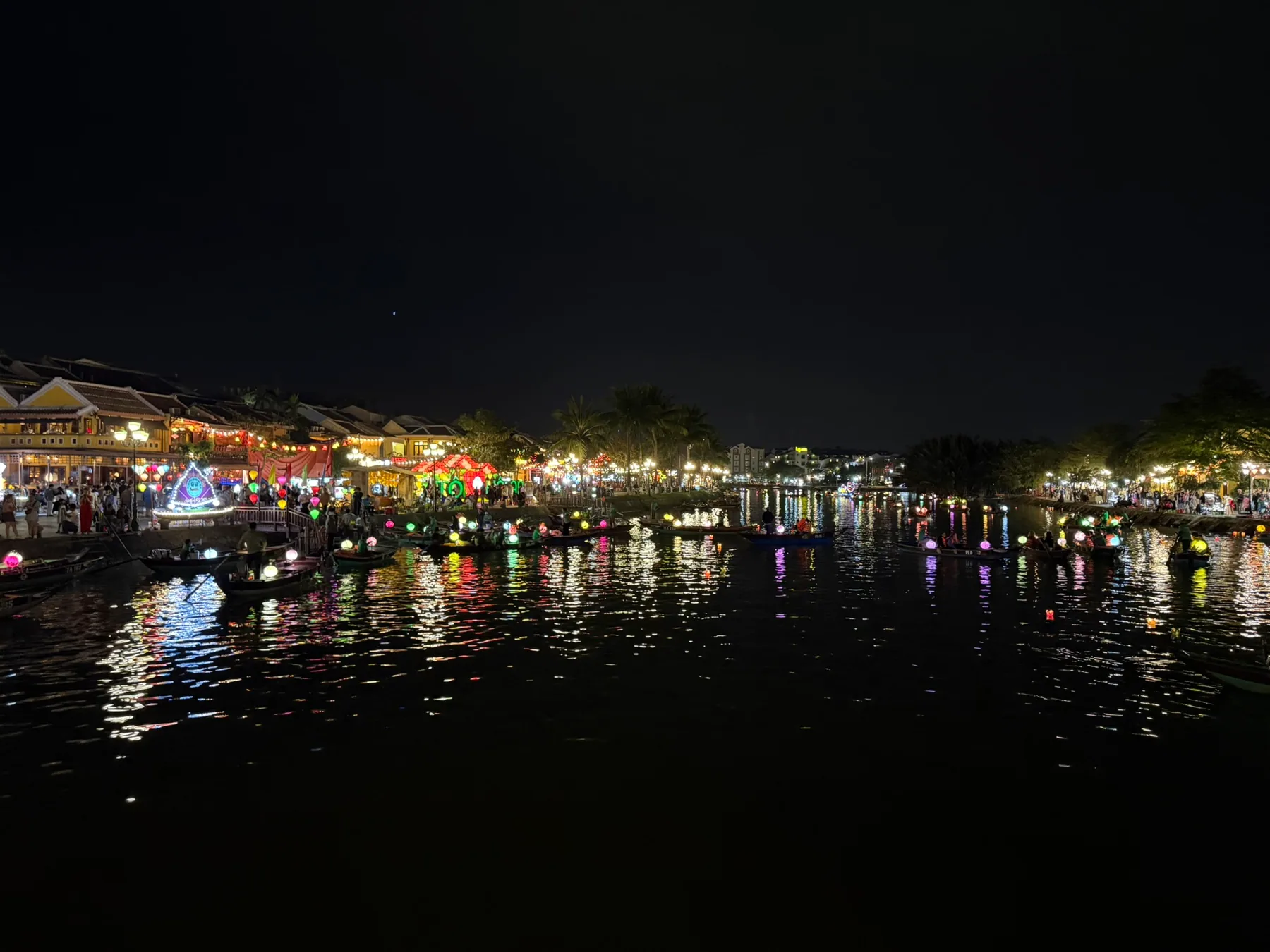 Lantern reflections glowing across the river in Hội An at night.